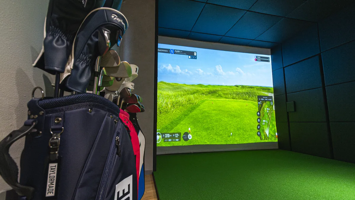 T-One Golf Studioのレンタルクラブが入ったキャディバッグと打席のスクリーン