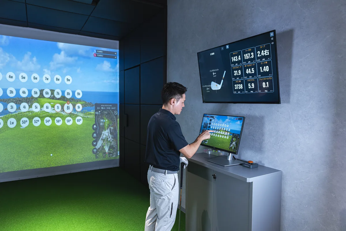 T-One Golf Studioの打席 TrackManのデータを壁の画面と手元のモニターで確認するゴルファー